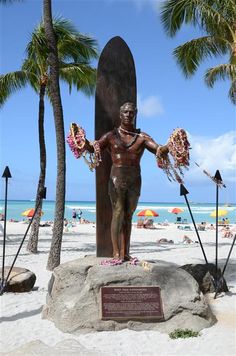 a man standing next to a surfboard on top of a sandy beach