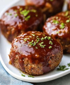 meatballs covered in marinara sauce and parsley on a white plate with a blue napkin