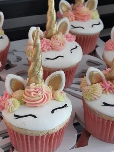 cupcakes decorated with pink frosting and gold unicorn ears are sitting on a table