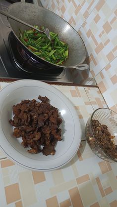 a bowl of food sitting on top of a table next to a pan filled with vegetables