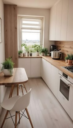 a kitchen with wooden floors and white cabinets, potted plants on the window sill