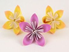 three paper flowers sitting on top of each other in front of a white background,