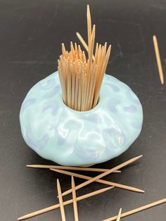 toothpicks are placed in a blue bowl on a black surface with wooden skewers