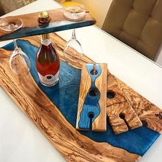 a bottle of wine sitting on top of a wooden tray next to two glasses and a corkscrew