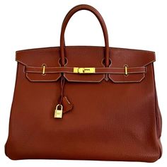 Gorgeous, authentic Hermès 40cm Birkin. Brick-colored Togo leather with gold hardware. Features the iconic dual-belt turnstile lock closure. Togo leather is a type of calfskin leather with an incredibly fine grain, known for its softness and resistance to scratching. The "E" blind stamp on interior of the right belt dates the bag back to 2001. Comes with original lock and keys, as well as its original dust bag, rain cover and Entrupy certificate. This bag is in lovely condition. 9.5+/10. It is s Hermes 2002 Bag, Timeless Togo Leather Bag With Lock, Formal Togo Leather Bag With Lock, Rectangular Togo Leather Bag With Gold-tone Hardware, Epsom Leather Travel Bag With Hasp Closure, Office Togo Leather Bag With Lock, Formal Togo Leather Bag With Gold-tone Hardware, Timeless Togo Leather Office Bag, Gold Epsom Leather Bag With Lock