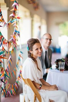 a woman sitting in a chair next to a table with paper streamers hanging from the ceiling