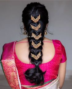 a woman with long black hair wearing a pink saree and gold jewelry on her head