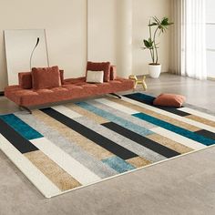 a living room with a couch, rug and potted plant on the floor in it