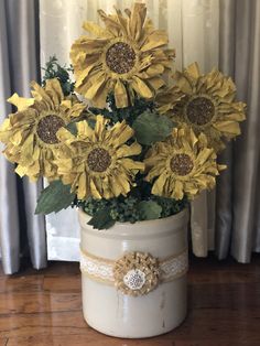 sunflowers in a white vase on a wooden floor