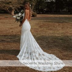 a woman in a white wedding dress standing on the grass with her back to the camera