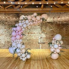 balloons and greenery are arranged in the shape of the letter o on a wooden floor