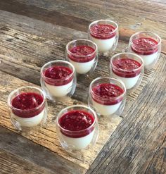 six glasses filled with pudding sitting on top of a wooden table next to each other