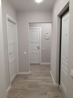 an empty room with white doors and wood flooring on either side of the door