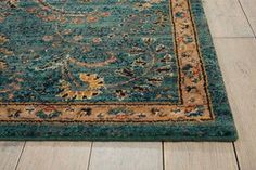 a blue rug with an ornate border on the floor in front of a wooden floor