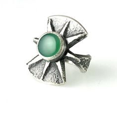 "Chrysoprase Tufa Cast Silver Ring Tufa cast silver ring with gem quality Chrysoprase and carved design this combination of traditional primitive techniques along with contemporary sculpting and simple strong lines makes timeless statement. This is a true one-of-a-kind statement ring of heavy silver and striking design. Measurements: Ring Fits approximate size 9 3/4 The top with the chrysoprase measures 1 1/8\" x 1\".  Band Measures approximate 3/8\" at the widest point and is tapered to approxi Modern Jade Cabochon Jewelry, Modernist Green Ring For Gift, Green Modernist Ring As A Gift, Modern Green Chrysoprase Jewelry, Green Modernist Ring As Gift, Modernist Green Ring As A Gift, Modernist Green Rings For Gift, Silver Chrysoprase Cabochon Emerald Ring, Unique Chrysoprase Ring With Large Stone