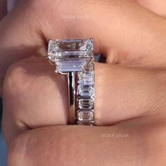 a woman's hand holding an engagement ring with three baguettes on it