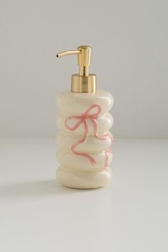 a soap dispenser with a pink ribbon on the front and gold faucet