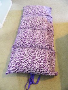 a purple and white blanket laying on the floor