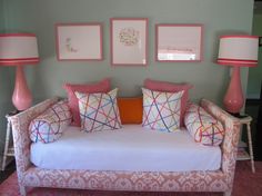 a couch with pillows and lamps on it in front of two framed pictures above the couch