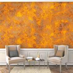 two chairs and a table in front of a wall with an orange paint design on it