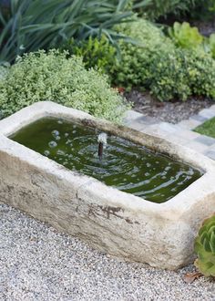 a stone water fountain in the middle of a garden