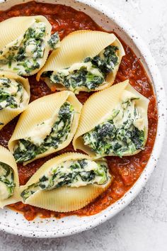 some ravioli with spinach and sauce in a white bowl