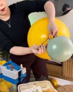 a woman is holding balloons in her hands