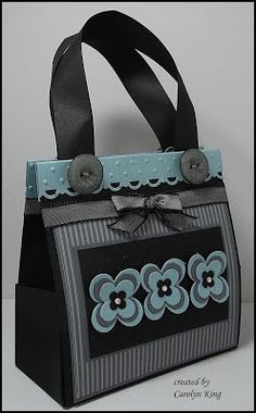 a black and gray bag with buttons on the handles is sitting in front of a white wall