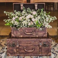 two suitcases are stacked on top of each other with flowers growing out of them