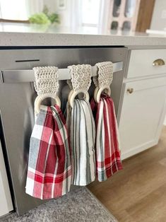 three kitchen towels hanging from the handle of a dishwasher