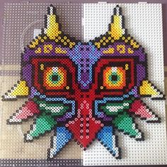 a close up of a cross stitch pattern on a wooden surface with an owl face