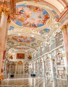 the interior of a library with many bookshelves and paintings on the ceiling above them