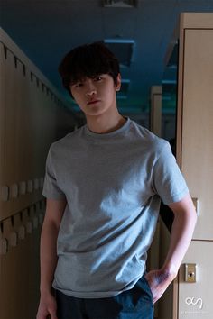 a young man standing in front of lockers with his hands on his hips and looking at the camera