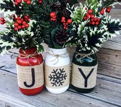 three jars with christmas decorations are sitting on a wooden bench, one has the letter y and the other is decorated with holly