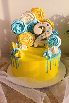 a yellow cake with blue and white icing on it's top is decorated with swirls and stars