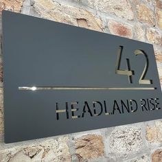 a metal sign that reads headland rise on it's side against a stone wall