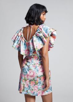 the back of a woman wearing a floral print dress with open shoulders and ruffled sleeves