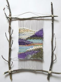 a piece of art made out of sticks and yarn on a white surface with branches