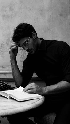 a man sitting at a table with a book and typewriter in front of him