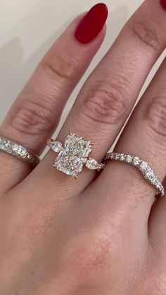 a woman's hand with two engagement rings on her fingers and one ring in the middle