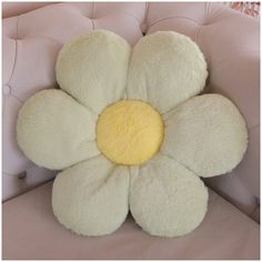 a stuffed flower sitting on top of a pink chair with yellow center and white petals