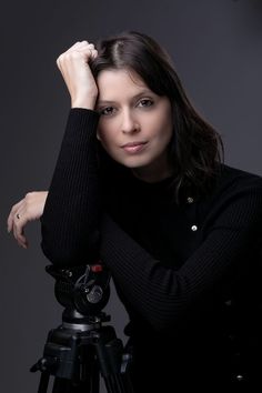 a woman leaning on a tripod with her hand on her head and looking at the camera