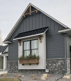 a gray house with white trim and window boxes on the windowsills is shown