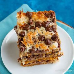 two pieces of chocolate and coconut bars on a white plate next to a blue napkin