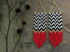 red, white and black beaded earrings hanging from gold hooks on a stone surface