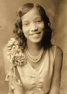 an old black and white photo of a young woman with pearls on her necklaces