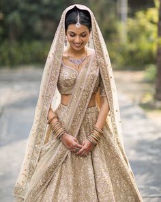 a woman in a bridal gown standing on the street with her hands clasped to her chest