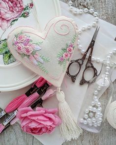 a heart shaped pillow sitting on top of a table next to some scissors and beads