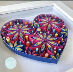 a decorative heart shaped box with candles in it's center on a white surface