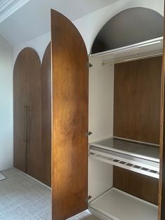 an empty closet with wooden doors and shelves